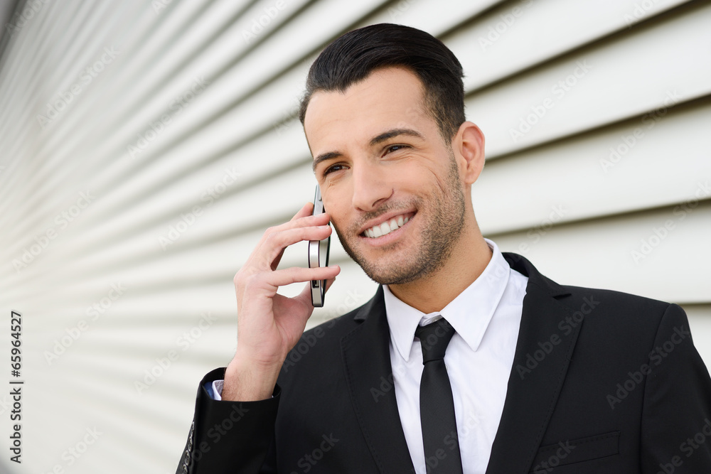 Attractive young businessman on the phone in an office building Attractive young businessman on the phone in an office building