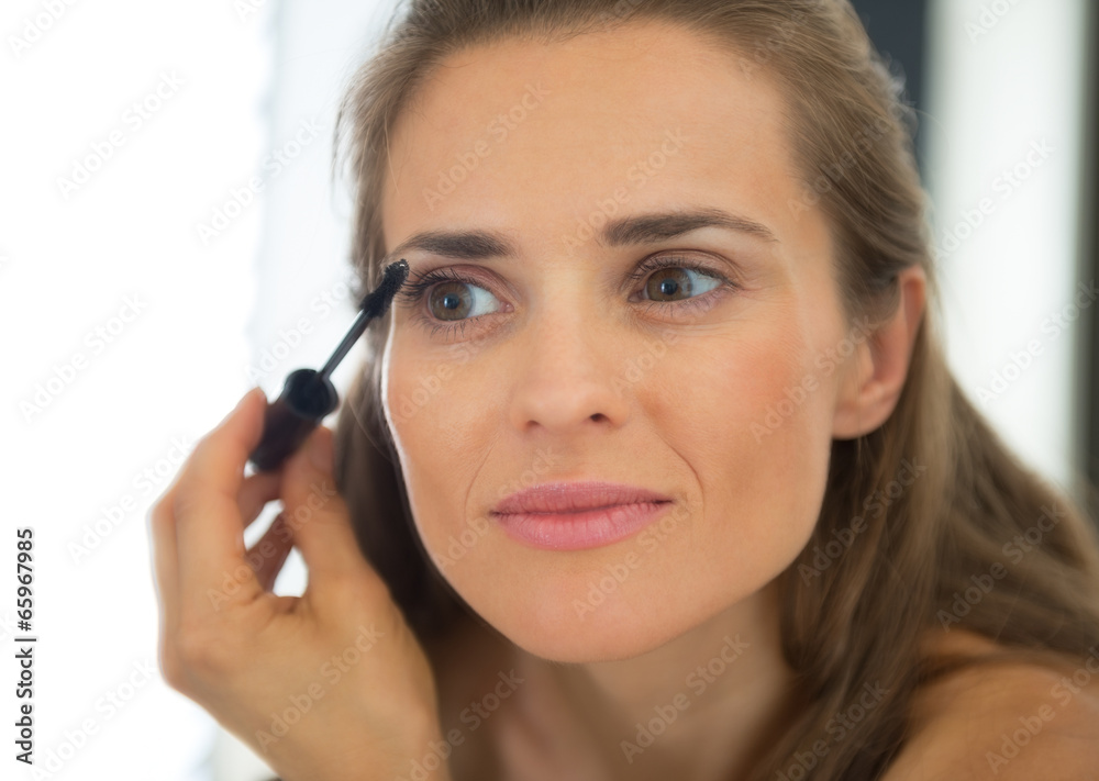 Portrait of young woman applying mascara Portrait of young woman applying mascara