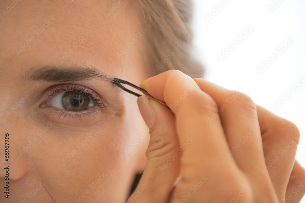Closeup on young woman tweezing eyebrows Closeup on young woman tweezing eyebrows