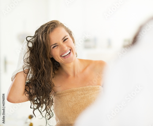 Portrait of smiling young woman wiping hair with towel