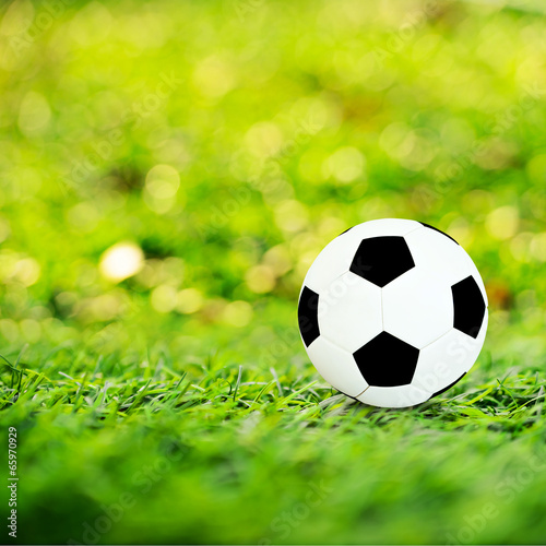 Ball on soccer field with orange bokeh and sun flare