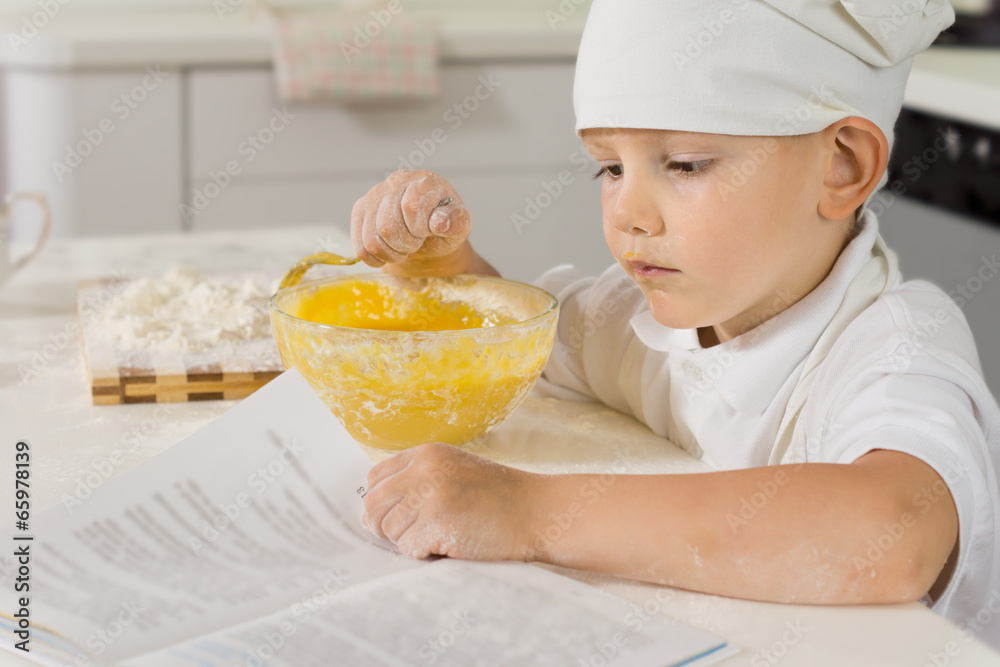 Cute small boy reading a recipe as he cooks Cute small boy reading a recipe as he cooks