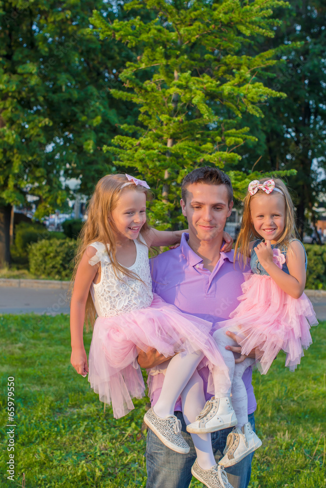 Naklejka premium Young Father and his adorable daughters having fun outdoors