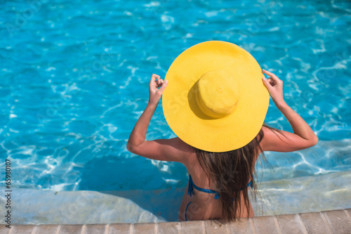 Woman in yellow hat relaxing at swimming pool