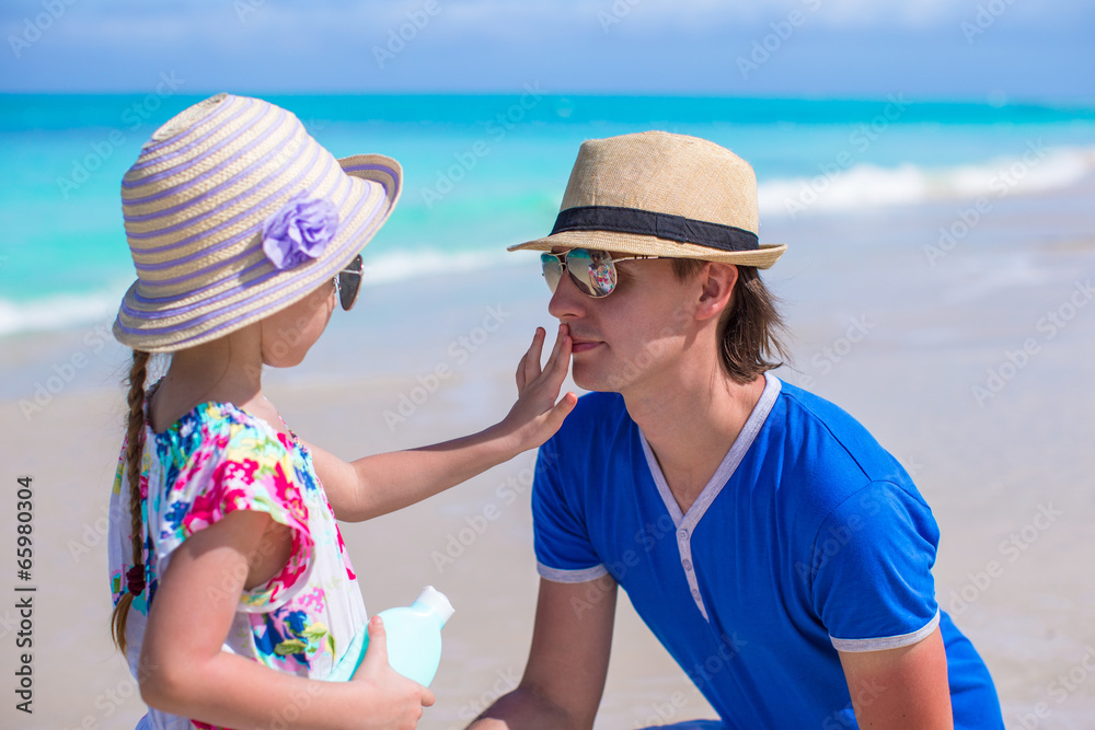 Little girl gets sun cream on her father's nose