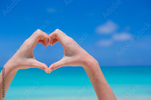 Closeup of heart made by hands background turquoise water © travnikovstudio
