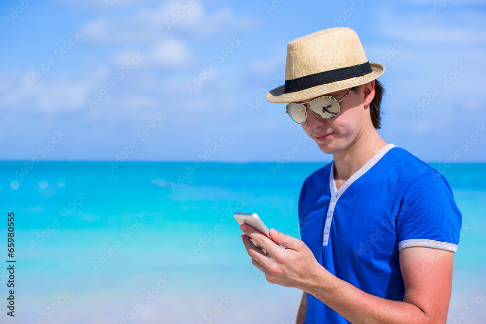 Young happy businessman with his phone on beach vacation