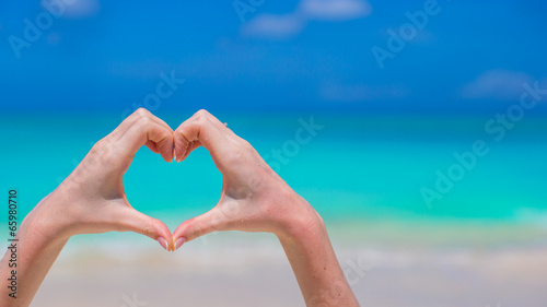Closeup of heart made by hands background turquoise water