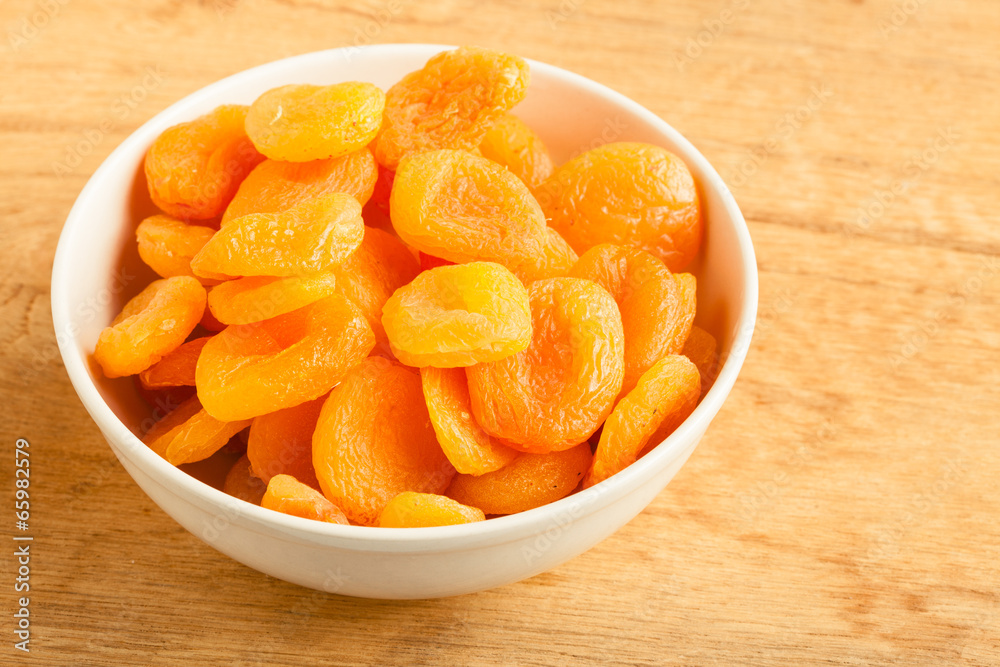 Bowl of dried apricots on wooden table background. Bowl of dried apricots on wooden table background.