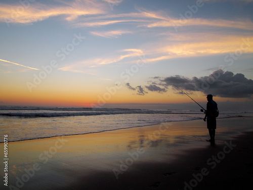 Sunset, beach and fishing man