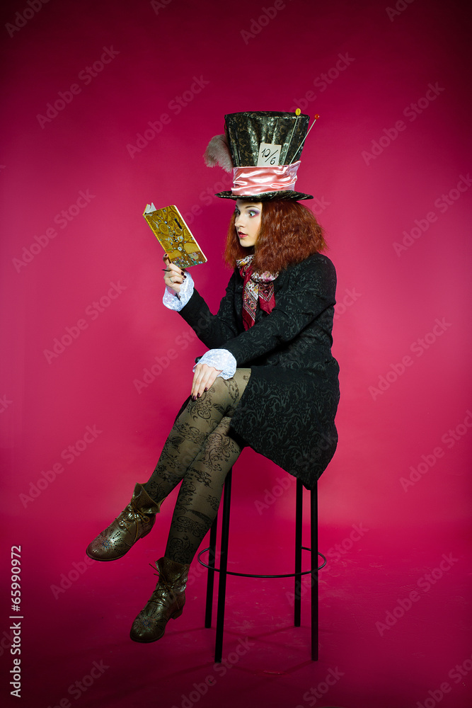 Fototapeta premium Young woman in the similitude of the Hatter reading book sitting