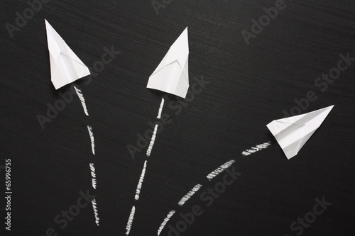 Fotografi Three paper airplanes take flight across a blackboard