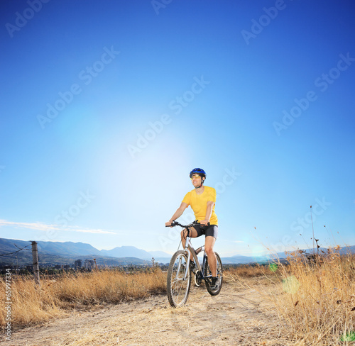 Young biker riding mountain bike in a field
