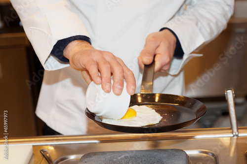 Chef is frying eggs on pan