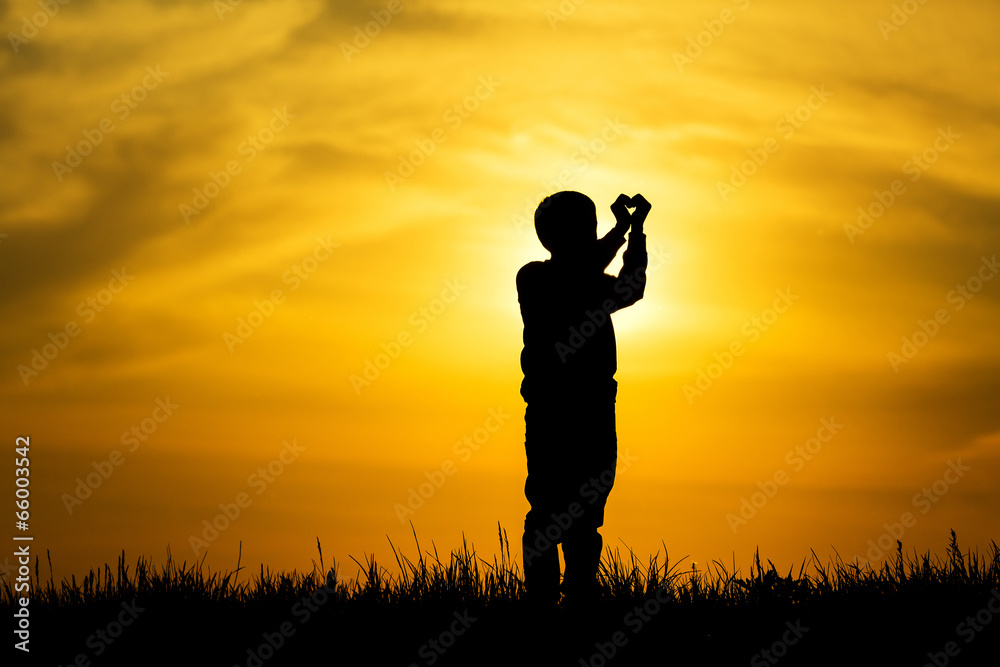 Silhouette boy hands making a heart