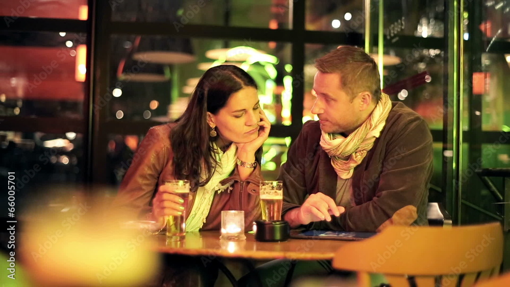 Couple watching photos on tablet computer in bar Couple watching photos on tablet computer in bar