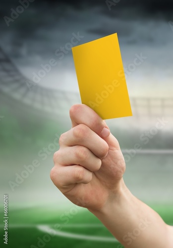 Composite image of hand holding up yellow card