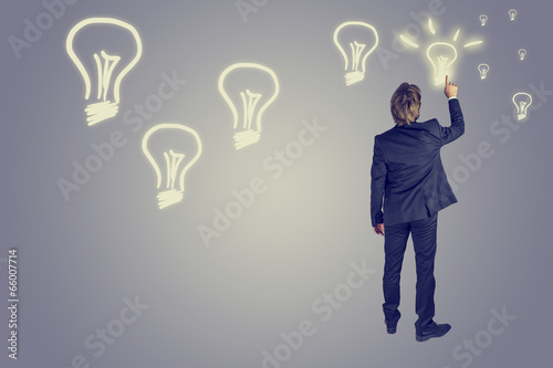 Businessman drawing light bulbs in the air