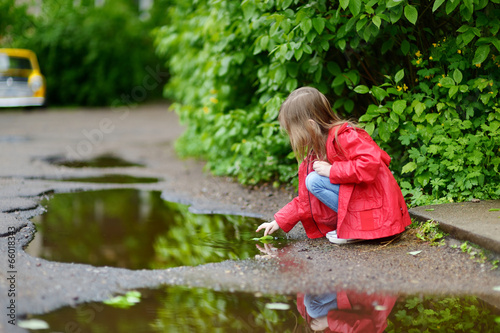 Ad girl playing in a puddle on rainy summer day