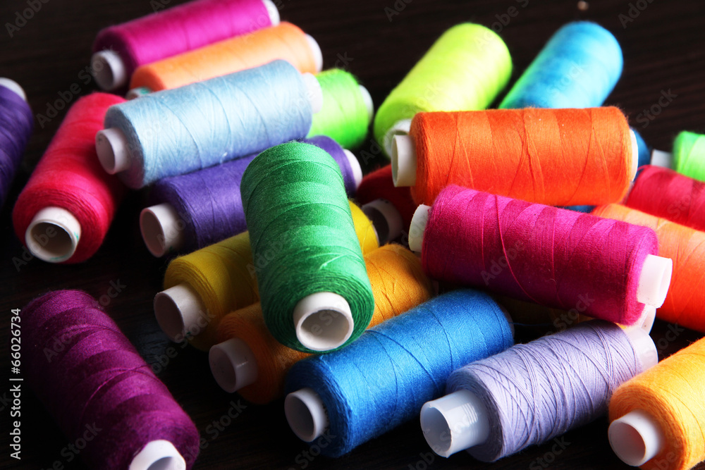 Multicolor sewing threads on wooden background Multicolor sewing threads on wooden background