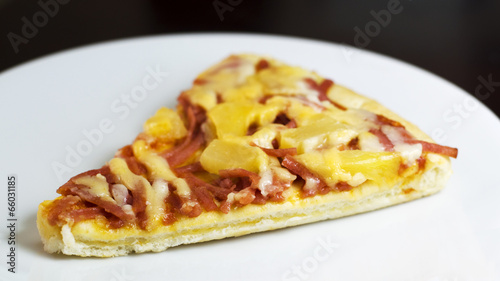 slice of fresh baked pizza hawiian on white dish