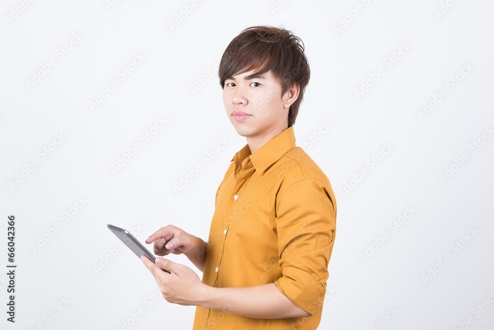Handsame man in orange shirt playing tablet Handsame man in orange shirt playing tablet
