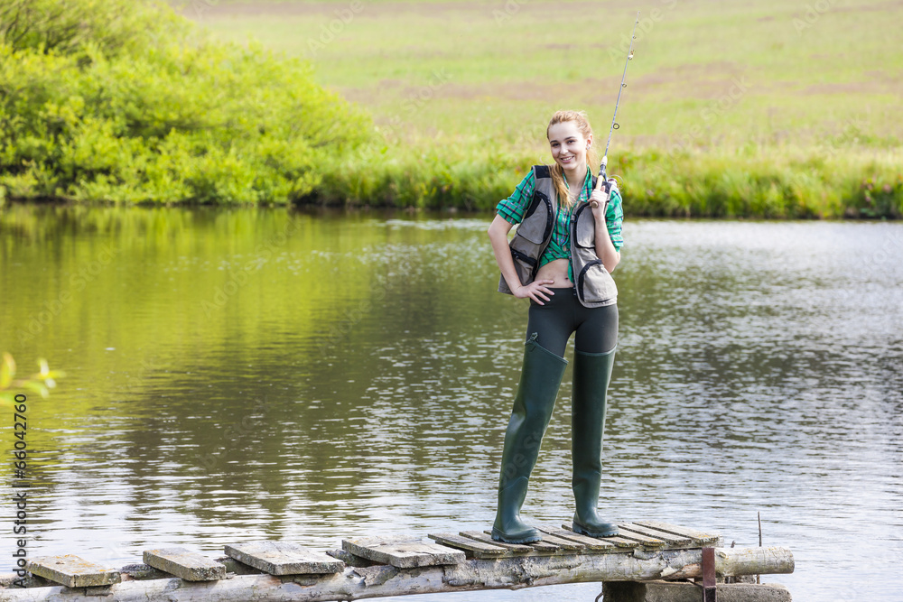 young woman fishing on pier at pond young woman fishing on pier at pond