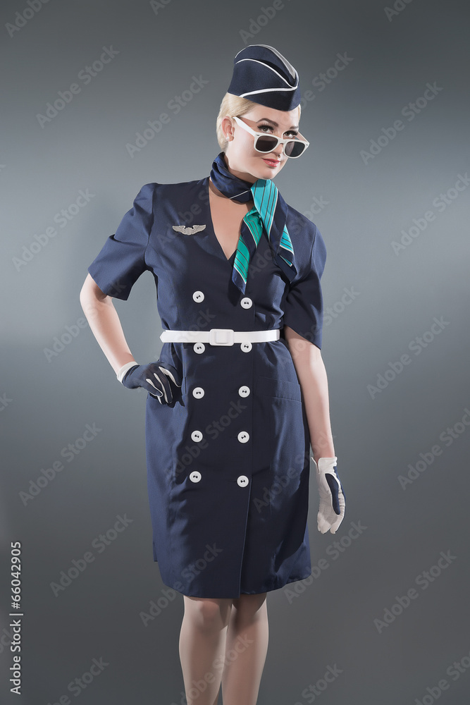 Smiling retro blonde stewardess wearing blue suit. Wearing white Smiling retro blonde stewardess wearing blue suit. Wearing white