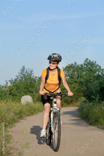 Happy adult woman riding bicycle outside.