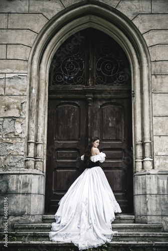 Mysterious woman in Victorian dress with old doors