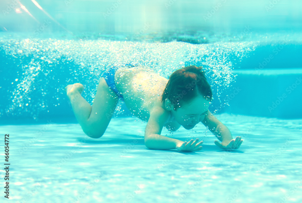 happy kid dives underwater in the pool