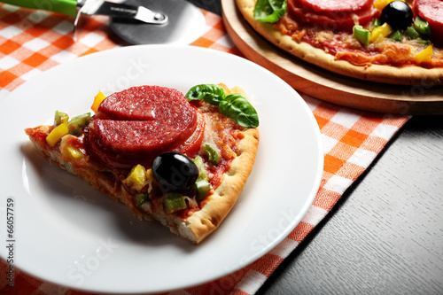 Pizza with tomato, salami, olives and basil on a plate