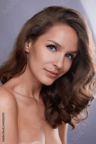 Portrait of young girl with curly dark hair and bare shoulders