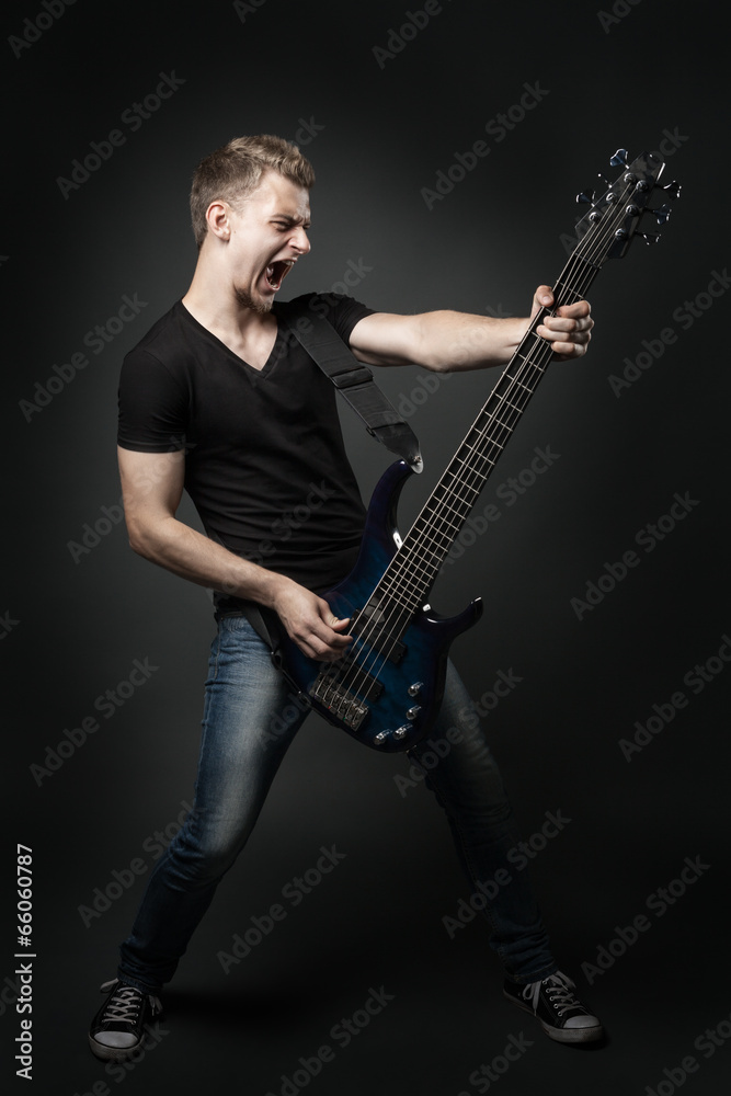 young male musician playing a six-string bass guitar isolated on young male musician playing a six-string bass guitar isolated on