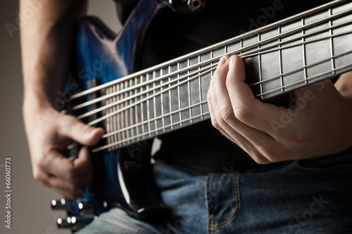 male musician playing on six-string bass guitar