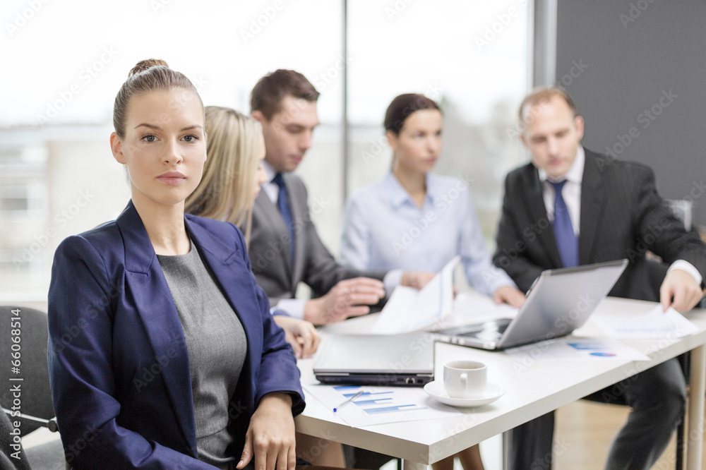businesswoman in office with team on the back businesswoman in office with team on the back