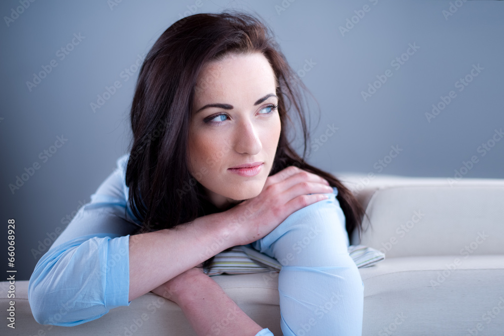 Naklejka premium cheerful young brunette lying on her sofa relaxed at home