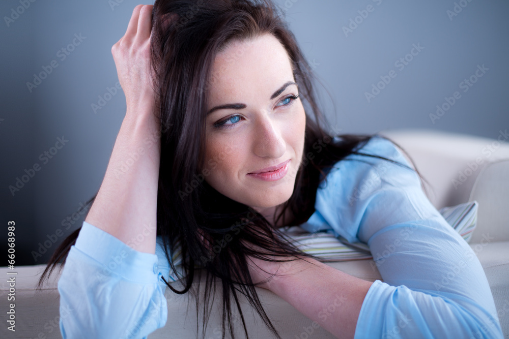 Fototapeta premium cheerful young brunette lying on her sofa relaxed at home