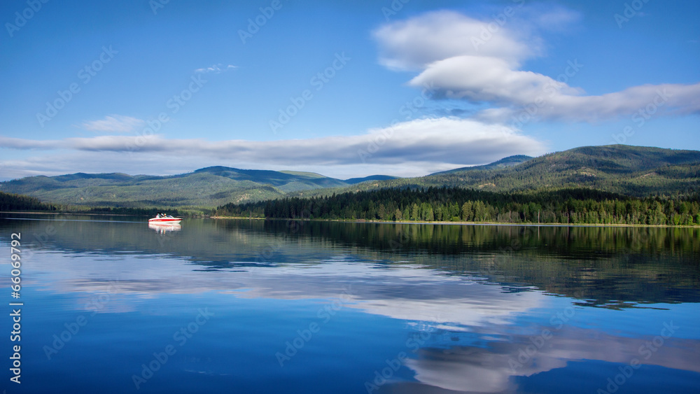Boat on morning lake with clouds and reflection