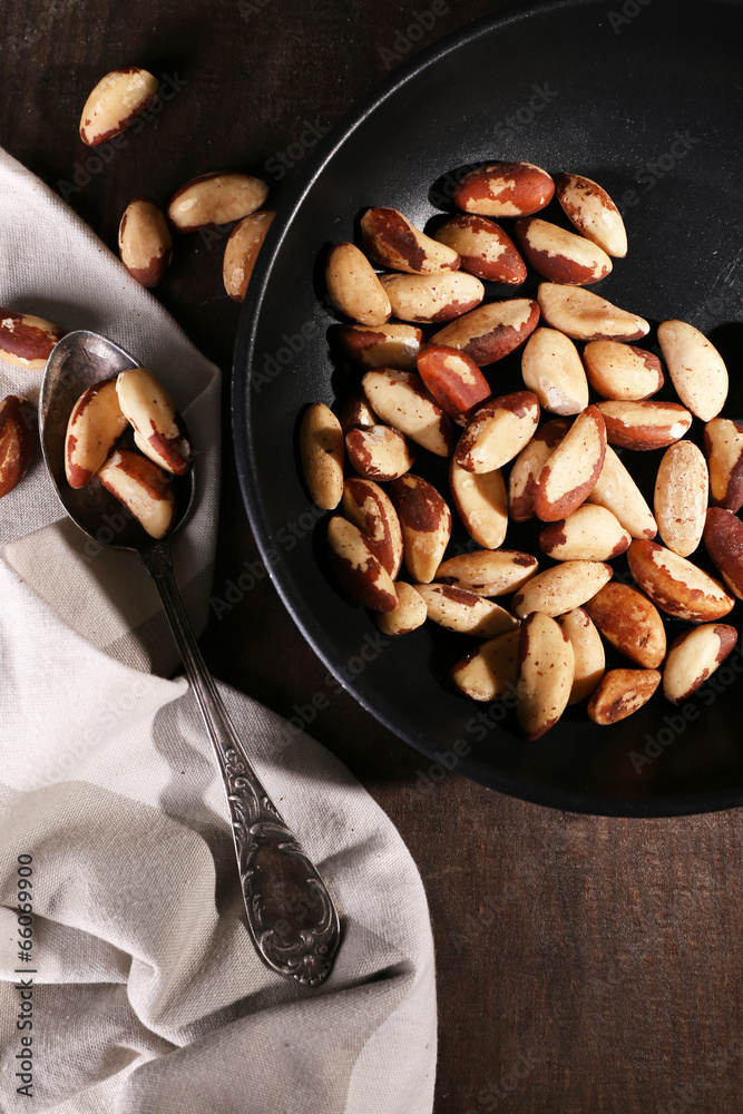 Tasty brasil nuts in pan on wooden background Tasty brasil nuts in pan on wooden background