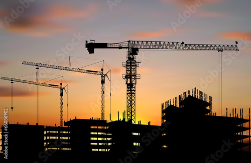 hoisting cranes above buildings at sunset