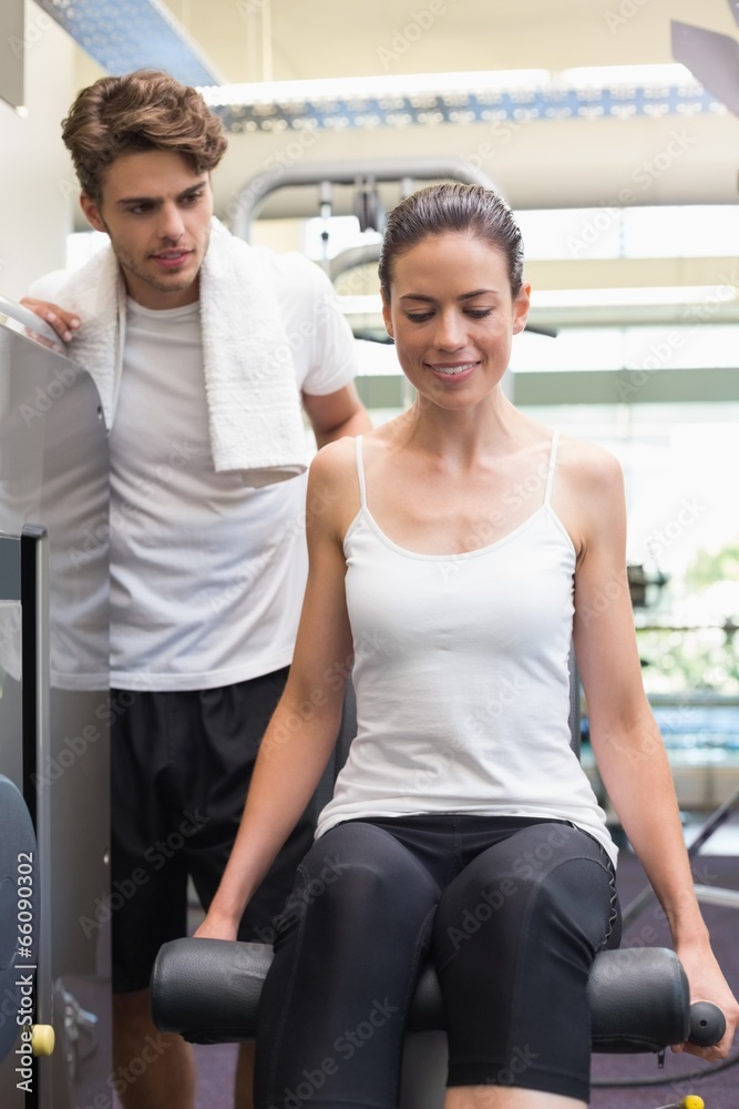 Fit brunette using weights machine for legs with trainer watchin Fit brunette using weights machine for legs with trainer watchin