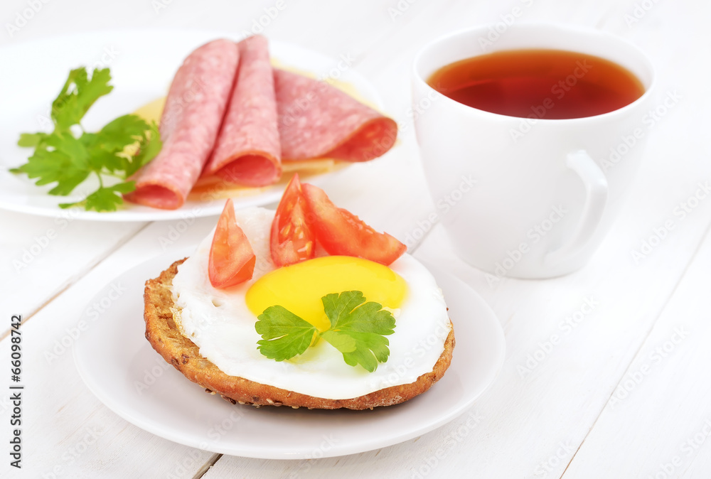 Sandwich with fried egg, tomato slices and tea Sandwich with fried egg, tomato slices and tea