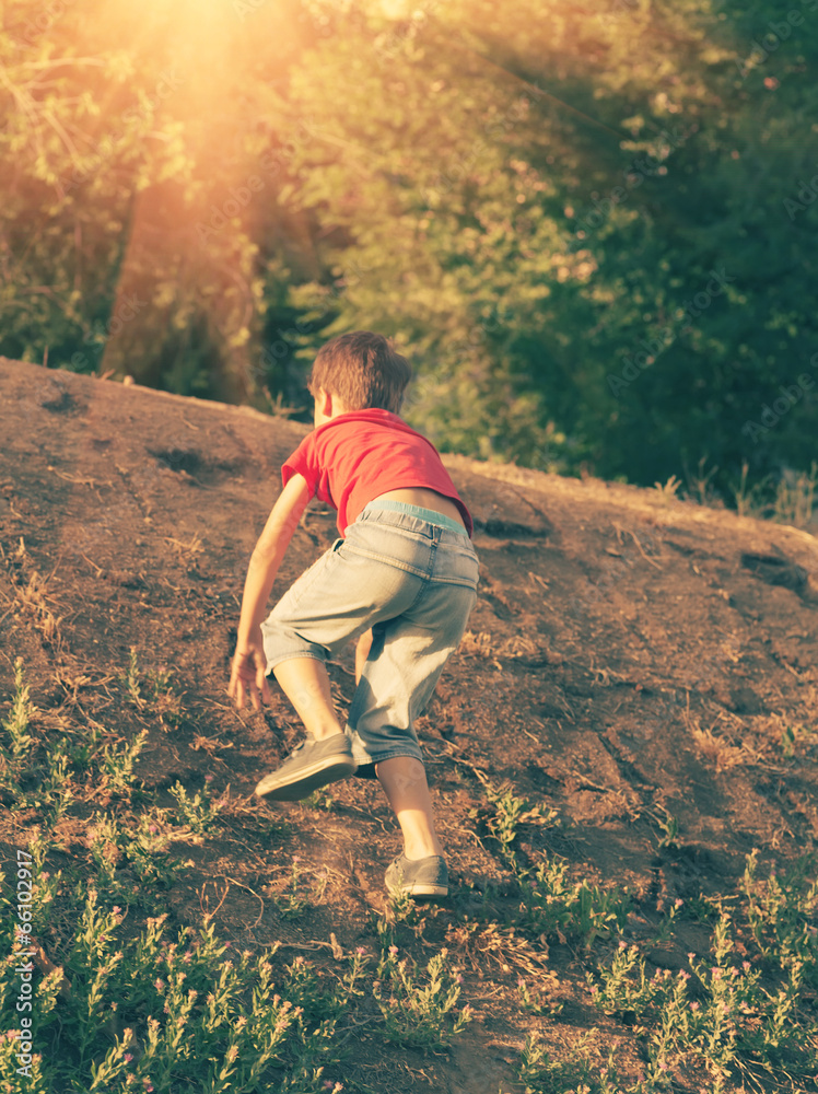Naklejka premium Boy climbing up the slope backlit