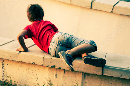 Boy playing on a cemet parapet photo