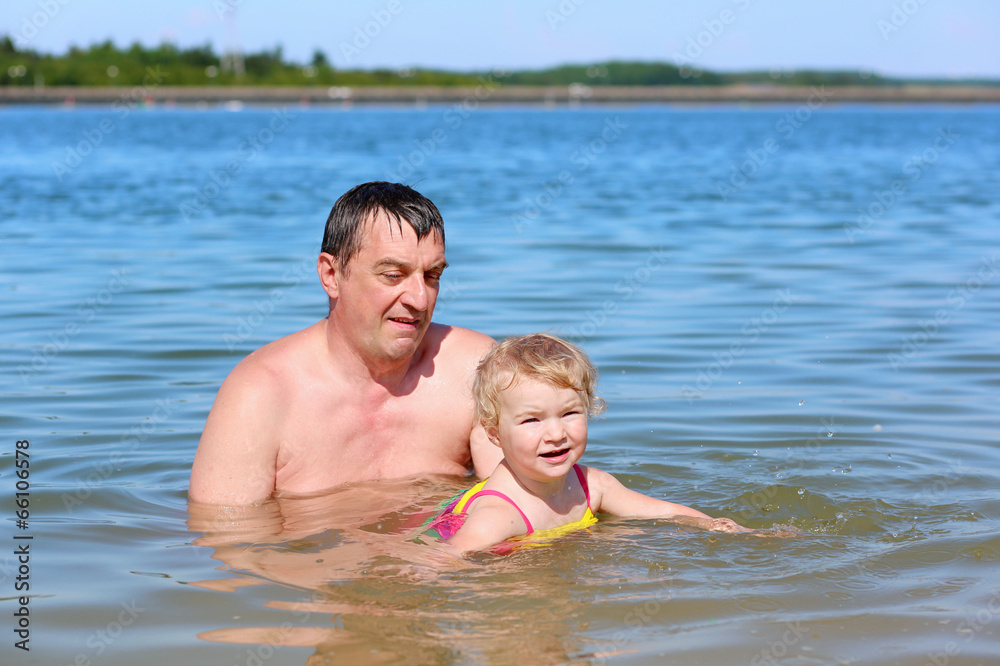 Father and little daughter swimming in the lake on summer day Father and little daughter swimming in the lake on summer day