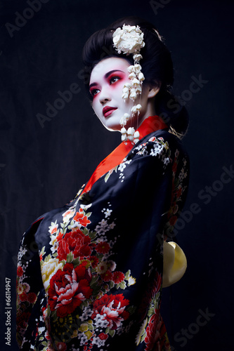 young pretty geisha in kimono with sakura and decoration on black background