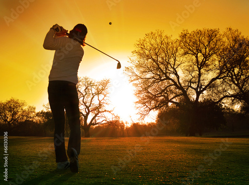golfer play stroke into setting sun