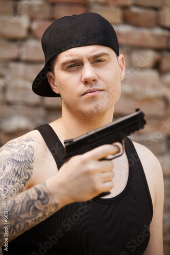 young guy with tattoo holding gun. photo