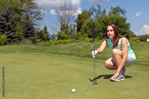 Fotografi Woman lining up her putt on the golf green